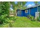 Exterior side view of a blue house with a well-maintained lawn, mature trees, and lush foliage at 217 W Powhatan Ave, Tampa, FL 33604
