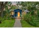 Charming blue home with lush landscaping, walkway and bright yellow door at 217 W Powhatan Ave, Tampa, FL 33604