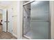 Bathroom featuring a glass-door shower with stone-look tile, hardwood floors and white walls at 2308 Cape Bend Ave, Tampa, FL 33613