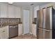 Bright kitchen featuring stainless steel refrigerator, tile floors, granite countertops, mosaic backsplash and bright white cabinets at 2848 Homewood St, Clearwater, FL 33759