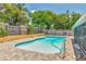 Inviting pool area with brick pavers and a screened enclosure, surrounded by lush greenery and a wooden fence at 2848 Homewood St, Clearwater, FL 33759
