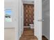View into the bathroom displaying hardwood floors and vertically stacked multi-colored wooden patterned wallpaper at 29245 Fedora Cir, Brooksville, FL 34602