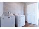 Well-lit laundry room featuring modern washer and dryer, wood-look flooring, and designer wallpaper at 29245 Fedora Cir, Brooksville, FL 34602