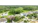 Street-level aerial view of three single Gathering homes, pond and treeline behind, lawns, and driveways at 3025 Winglewood Cir, Lutz, FL 33558