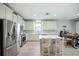 Bright kitchen featuring an island with seating, stainless appliances, white cabinets, and light floors at 3025 Winglewood Cir, Lutz, FL 33558