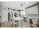 Bright kitchen featuring an island with seating, stainless appliances, white cabinets, and light floors at 3025 Winglewood Cir, Lutz, FL 33558