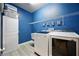 Modern laundry room with blue walls, white cabinets, and state-of-the-art washer and dryer at 3025 Winglewood Cir, Lutz, FL 33558