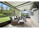 Enclosed patio has cozy seating, ceiling fan and views of the green backyard at 3025 Winglewood Cir, Lutz, FL 33558