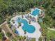 Aerial view of a community pool area with multiple pools, palm trees, lounge chairs, and a playful water slide at 3603 Tour Trce, Land O Lakes, FL 34638