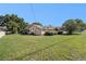 Large backyard with lush grass and trees and a glimpse of the home's exterior at 4355 Odin St, Spring Hill, FL 34608