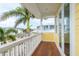 View from the wood balcony with a white railing and yellow siding with views of palm trees and other homes at 442 Midway Is, Clearwater Beach, FL 33767