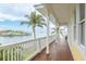 Waterfront balcony with white railings and wood floors offers panoramic views of bay and tropical foliage at 442 Midway Is, Clearwater Beach, FL 33767