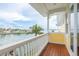 A charming balcony with wood floors and a water view with a palm tree and houses in the distance at 442 Midway Is, Clearwater Beach, FL 33767