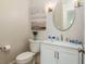 Bright powder room featuring a white vanity and round mirror with neutral decor at 442 Midway Is, Clearwater Beach, FL 33767