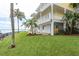 Expansive yellow home exterior with multiple decks, lush green lawn, and waterfront access at 442 Midway Is, Clearwater Beach, FL 33767