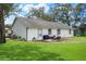 Exterior rear view of house with white siding, green trim, patio, lush lawn, and privacy fencing at 5301 Bayonne Ave, Spring Hill, FL 34608