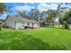 Well-maintained backyard with lush green grass, mature trees, patio and white exterior of home at 5301 Bayonne Ave, Spring Hill, FL 34608