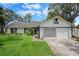 Charming single Gathering home with beautiful lawn, white siding, green trim, and attached two car garage at 5301 Bayonne Ave, Spring Hill, FL 34608