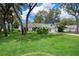 Well-manicured front yard with mature trees shading a white single Gathering home with attached garage at 5301 Bayonne Ave, Spring Hill, FL 34608