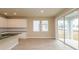 Open-concept living space with sliding glass doors, wood-look floors, and white kitchen cabinets at 5909 Bibb Ct, North Port, FL 34288
