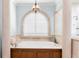 Bathroom featuring a soaking tub under an arched window with custom shutters at 611 1St S Ave, Tierra Verde, FL 33715