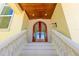 Elegant front entrance with arched double doors, stone steps, and decorative railings enhancing curb appeal at 611 1St S Ave, Tierra Verde, FL 33715