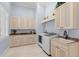 Well-lit laundry room with custom cabinets, a utility sink, and a modern washer and dryer at 611 1St S Ave, Tierra Verde, FL 33715