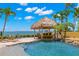Tropical backyard with a custom tiki bar overlooking the pool and waterfront at 611 1St S Ave, Tierra Verde, FL 33715