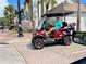 Street view of a Personal driving a red golf cart near a church and brick building at 702 Lyndhurst St # 822, Dunedin, FL 34698