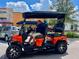 Street view of a Personal driving an orange golf cart, stores, and a cloud filled sky at 702 Lyndhurst St # 822, Dunedin, FL 34698