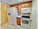 Spacious kitchen featuring white appliances including a refrigerator, oven, microwave, and wooden cabinets at 702 Lyndhurst St # 822, Dunedin, FL 34698