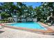 Community pool area with shade trees and comfortable lounge seating at 702 Lyndhurst St # 822, Dunedin, FL 34698