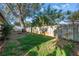 A grassy backyard is enclosed by a wooden fence, with a large tree providing shade and adding natural beauty at 7400 Locust Ne St, St Petersburg, FL 33702