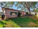 A large tree is a focal point in the well-maintained backyard, next to a neutral home with tidy landscaping at 7400 Locust Ne St, St Petersburg, FL 33702