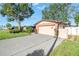 A single-story home with brick accents features a well-maintained lawn, mature trees, and a long driveway at 7400 Locust Ne St, St Petersburg, FL 33702