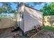 A backyard shed with light-colored horizontal siding features dark trim and a small window, surrounded by lush landscaping at 7400 Locust Ne St, St Petersburg, FL 33702