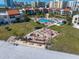 This aerial view shows a pool, beachfront access, well-manicured lawn, and several building exteriors with red roofs at 825 S Gulfview Blvd # 104, Clearwater Beach, FL 33767