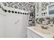 Bathroom with white tile, black and white wallpaper, and a vanity with ample storage at 8319 Annwood Rd, Seminole, FL 33777