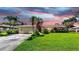 Charming single-story home with a lush green lawn, mature palm trees, and a two-car garage at 8671 11Th N St, St Petersburg, FL 33702