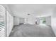 An open-concept living room with bright, neutral walls, plush carpet, and large, shuttered windows at 8671 11Th N St, St Petersburg, FL 33702