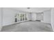 An open-concept living room featuring large windows with shutters and neutral-toned carpeting at 8671 11Th N St, St Petersburg, FL 33702