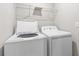 Modern laundry room featuring a white washer and dryer set with upper wire shelving at 9768 Pembrooke Pines Dr, Sun City Center, FL 33573