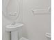 Simple powder room with a pedestal sink and round mirror offering functionality and style at 9768 Pembrooke Pines Dr, Sun City Center, FL 33573