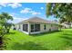 Home's backyard featuring green grass and a screened-in lanai at 10597 Alvarado Ct, Seminole, FL 33772