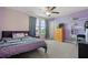 Bedroom with a ceiling fan, lavender walls, a large window, and a soft bedspread at 11024 Purple Martin Blvd, Riverview, FL 33579