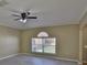 A bright living room with a window looking out into the fenced backyard and light colored walls at 11438 Ivy Flower Loop, Riverview, FL 33578