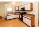 Well-lit kitchen with white cabinets, black appliances, and light wood floors at 11945 Darwin Ave, New Port Richey, FL 34654