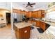 Bright kitchen featuring wooden cabinets, granite countertops, stainless steel appliances, and center island with breakfast bar at 11945 Darwin Ave, New Port Richey, FL 34654