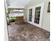 Charming covered patio with brick flooring, a wooden bench, and double French doors leading indoors at 11945 Darwin Ave, New Port Richey, FL 34654