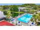 Aerial view of community pool, tennis courts and pond, surrounded by lush greenery at 1207 Pine Ridge W Cir # H2, Tarpon Springs, FL 34688